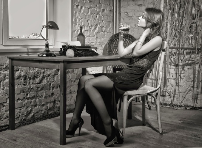 Elegant woman in black at the table with the old typewriter